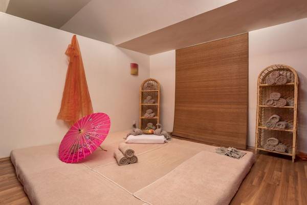Yoga-Raum im Seven Seas Hotel Life mit Meditationskissen, Handtüchern und einer pinken Regenschirm.