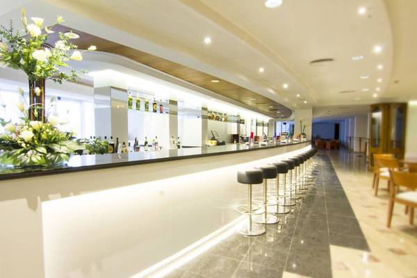 Bar im CM Castell de Mar Hotel mit weißen Stühlen und einer grünen Pflanze.