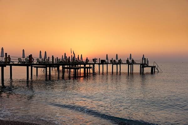 Sonnenuntergang am Pier des Seven Seas Hotel Life mit Liegen und Schirmen.
