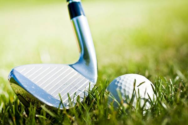 Golfschläger im Rasen neben einem weißen Golfball.