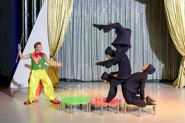 Artisten führen eine Show im Seven Seas Hotel Life auf, mit einem Mann in Clownkostüm und zwei Frauen in schwarzen Kostümen.