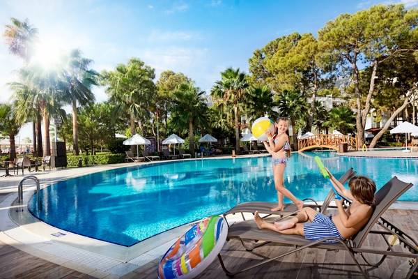 Zwei Kinder spielen am Pool im Seven Seas Hotel Life, umgeben von Palmen und Sonnenschirmen.