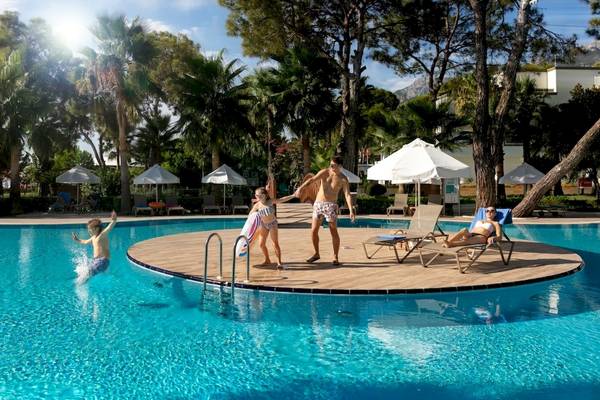 Familie am Pool im Seven Seas Hotel Life, darunter ein Mann, der ein Mädchen und einen Jungen anfeuert, eine Frau, die sich entspannt, und ein weiteres Kind, das ins Wasser springt.
