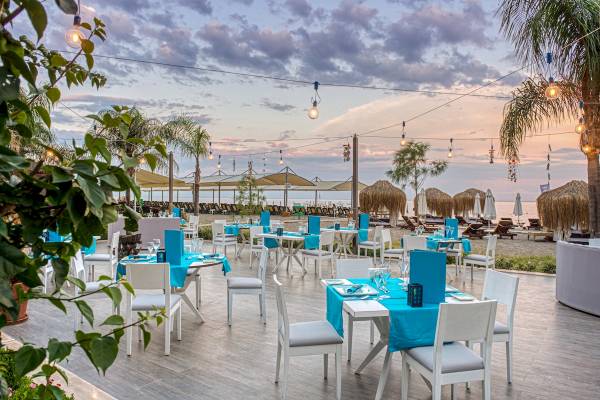 Terrasse des Seven Seas Hotel Life bei Sonnenuntergang mit blauen Tischdecken und Laternen.