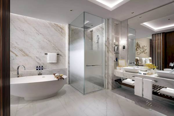 Badezimmer im Atlantis The Royal mit Badewanne, Glasdusche und Waschbecken.