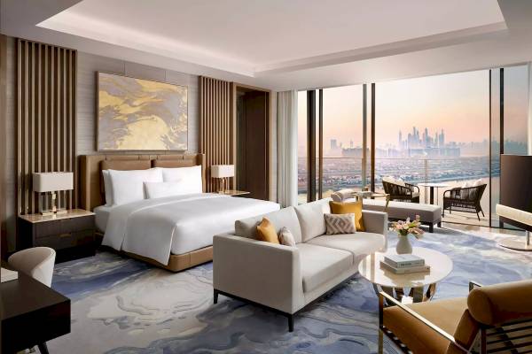 Innenansicht der Suite im Atlantis The Royal Hotel mit Bett, Sofa, Tisch und Aussicht auf die Stadt.