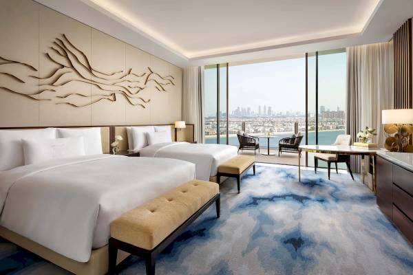 Innenansicht einer Suite im Atlantis The Royal Hotel mit zwei Betten, einem Schreibtisch und einer Aussicht auf die Stadt.