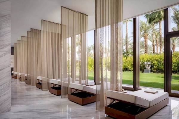 Innenansicht des Wellnessbereichs im Atlantis The Royal Hotel mit langen weißen Vorhängen und Betten.
