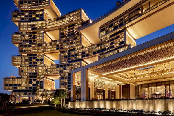 Nachtansicht des Atlantis The Royal Hotels mit beleuchteten Stockwerken und Wasserfall.