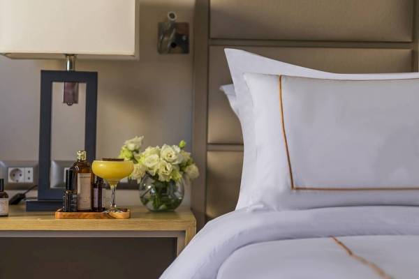 Hotelzimmer mit Bett, Blumen und Getränken auf Nachttisch