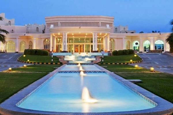 Haupteingang des Hilton Salalah Resorts bei Nacht mit Brunnen und Beleuchtung.