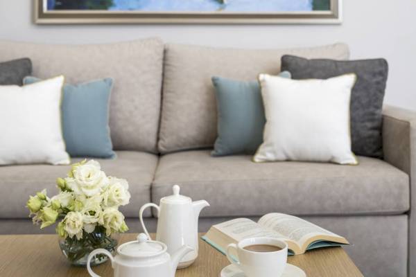 Hotel-Lounge mit Sofa, Tisch, Blumen, Teekannen und Kaffeetasse