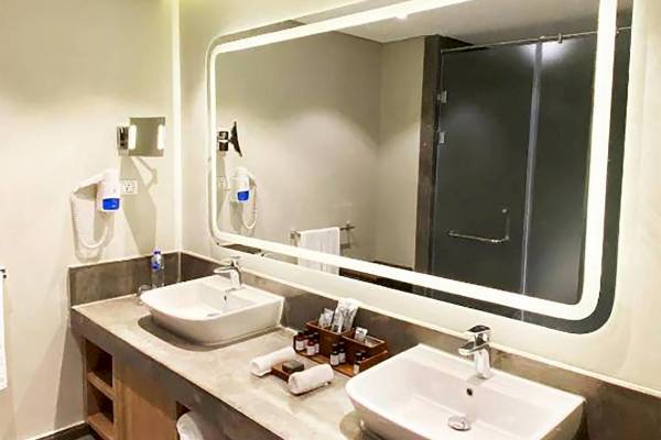 Hotelbadezimmer mit zwei Waschbecken, großem Spiegel und moderner Einrichtung.