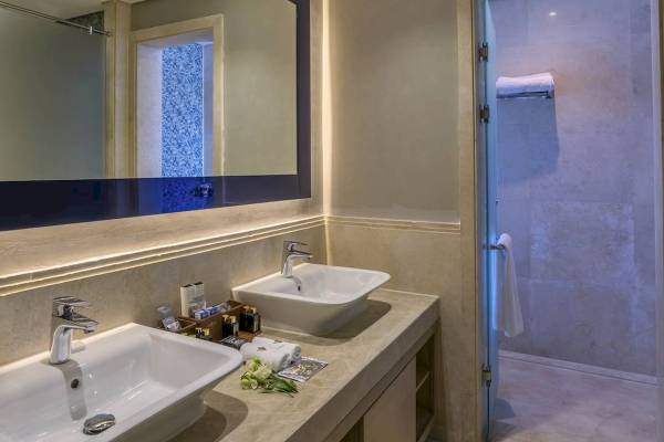 Badezimmer im Rixos Premium Magawish Suites & Villas mit zwei Waschbecken, Spiegel und Duschbereich.
