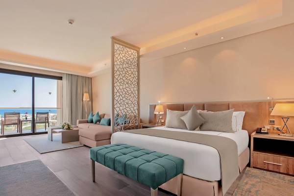 Schlafzimmer im Rixos Premium Magawish Suites & Villas mit Doppelbett, Sofa, Fenster und Meerblick.