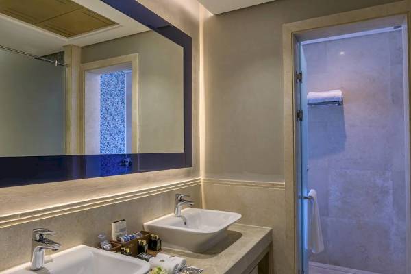 Badezimmer im Rixos Premium Magawish Suites & Villas mit Doppelwaschbecken und Dusche.