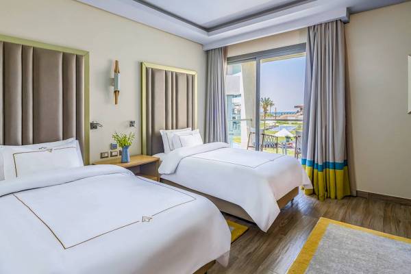 Zwei Doppelbetten in einem Hotelzimmer mit Meerblick im Rixos Premium Magawish Suites & Villas