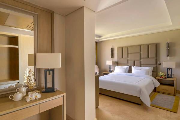 Luxuriöses Schlafzimmer im Rixos Premium Magawish Suites mit einem großen Bett und einem Ankleidezimmer.