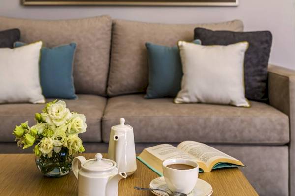 Sofa mit Blumen, Tee und Buch auf dem Tisch im Wohnzimmer.