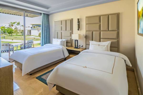 Doppelzimmer im Rixos Premium Magawish Suites & Villas mit Blick auf eine Terrasse und einen Garten.