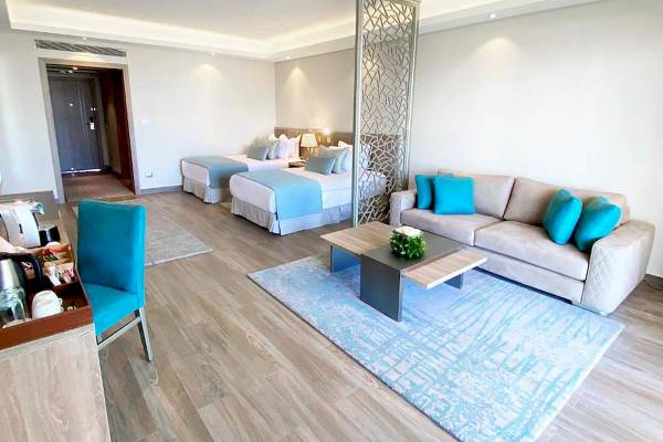 Wohnbereich der Rixos Premium Magawish Suites & Villas mit zwei Betten, einem Sofa und einem Tisch.