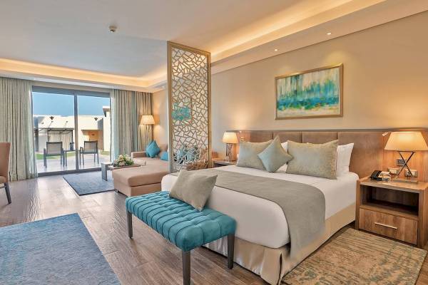 Luxuriöses Schlafzimmer im Rixos Premium Magawish Suites & Villas mit großem Bett, Kissen, Nachttischen und einer schönen Aussicht.