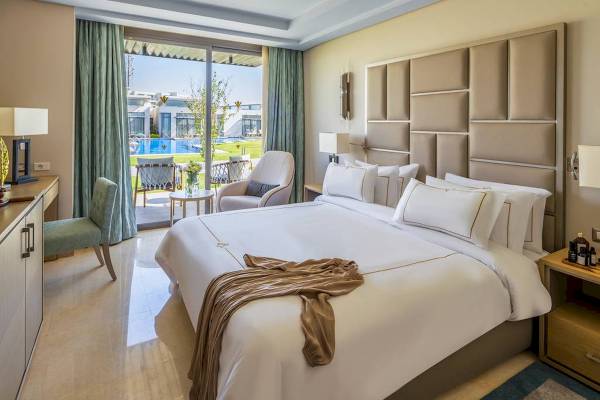Luxuriöses Schlafzimmer im Rixos Premium Magawish Suites & Villas mit Blick auf den Pool.