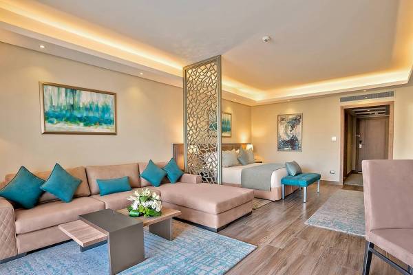 Innenansicht der Premium Suite und Villa im Rixos Hotel, mit Wohnzimmer, Bett, Teppich und Kunstwerken an der Wand.
