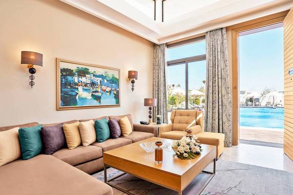 Hotellounge-Bereich mit Sofa, Couchtisch, Sessel, Gemälde und Pool-Aussicht.