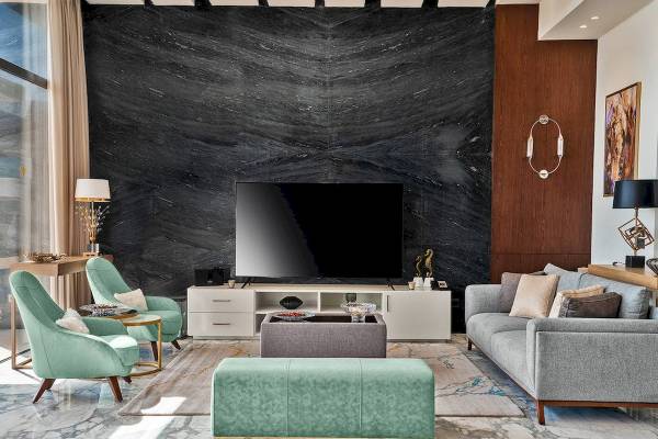 Wohnzimmer im Rixos Premium Magawish Suites & Villas mit schwarzem Marmorwand, Fernseher, Couch, Sesseln und Tischlampen.