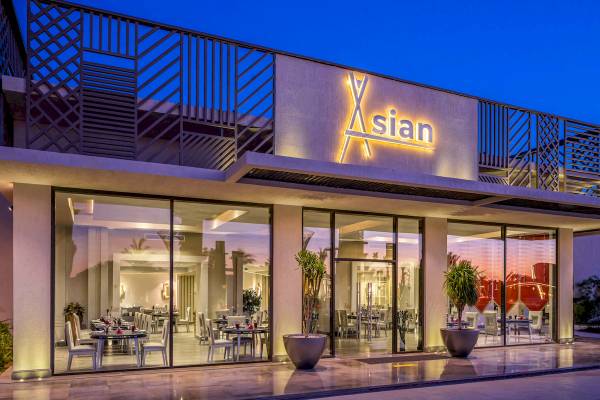 Außenansicht des Rixos Premium Magawish Suites & Villas Hotels bei Nacht mit beleuchtetem Logo.