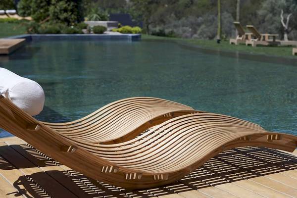 Eine geschwungene Holzliege am Pool des Mandarin Oriental, Costa Navarino