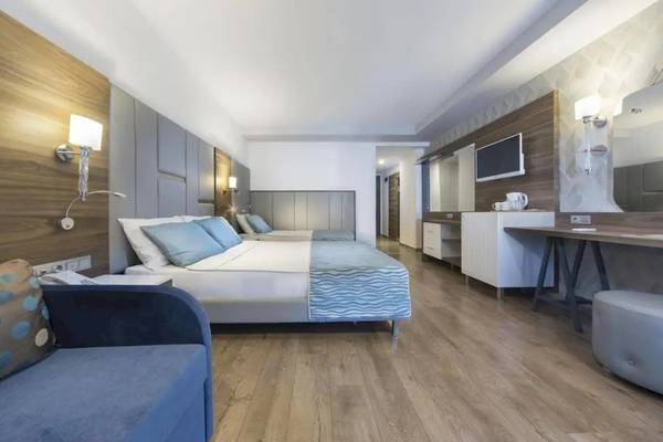 Inneneinrichtung eines Zimmers im Eftalia Ocean Hotel mit zwei Betten, Schreibtisch, Lampe und Couch.