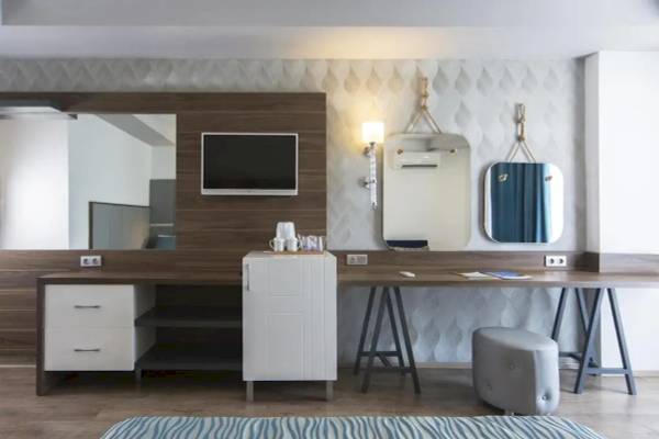 Inneneinrichtung eines Zimmers im Eftalia Ocean Hotel mit Schreibtisch, Spiegel und Fernseher.