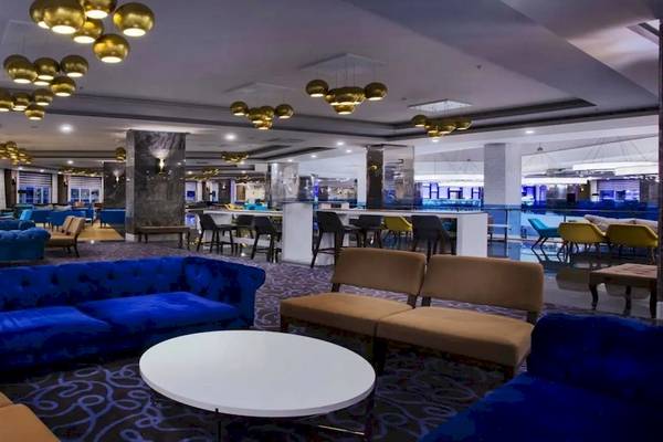Lobby des Eftalia Ocean Hotels mit blauen und braunen Sofas, runden Tischen und Kronleuchtern.
