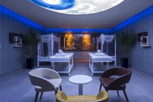 Massageraum im Eftalia Ocean Hotel mit zwei Massagebetten, einer Tisch, und einem Gemälde an der Wand.