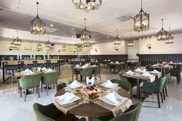 Innenansicht des Restaurants im Eftalia Ocean Hotel mit gedeckten Tischen und hängenden Kronleuchtern.
