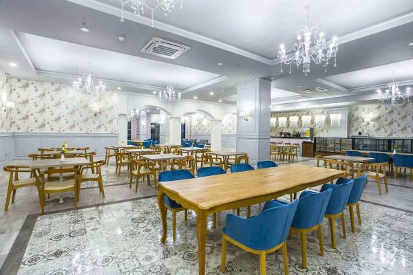 Innenansicht des Eftalia Ocean Hotels mit gemusterten Wänden, Holztischen und blauen Stühlen.