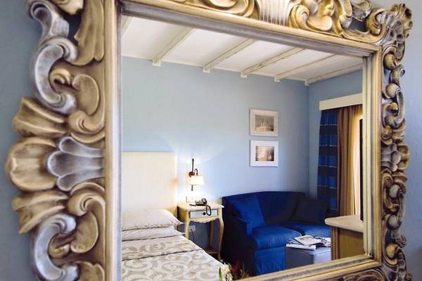 Spiegel im Hotelzimmer von CPH Pevero mit Blick auf ein Bett und ein Sofa