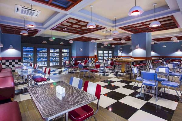 Restaurantbereich im Eftalia Ocean Hotel mit schwarz-weißen Bodenfliesen und roten und blauen Stühlen.