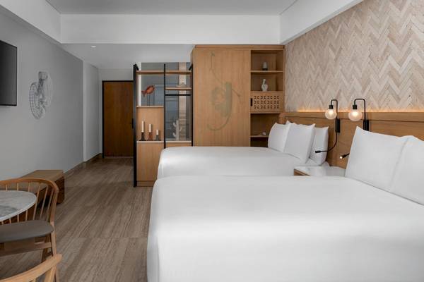 Schlafzimmer im Hilton Tulum Riviera Maya All-Inclusive Resort mit zwei Betten, Tisch, Stühlen und Fernseher.