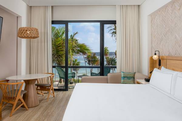 Zimmer im Hilton Tulum Riviera Maya All-Inclusive Resort mit Blick auf den Ozean und Terrassenmöbeln.