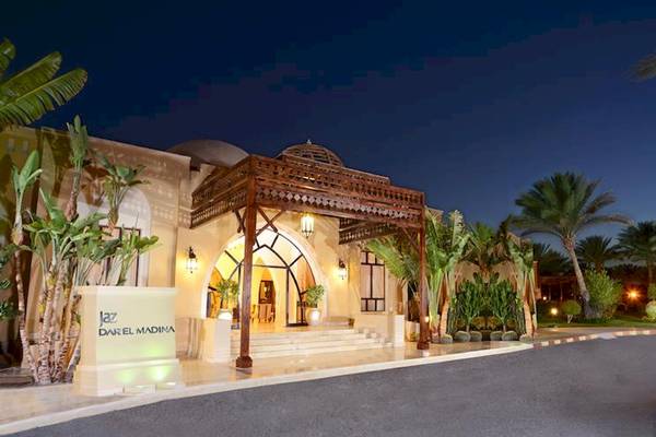 Eingang des Jaz Dar El Madina Hotels bei Nacht mit Palmen und Beleuchtung.