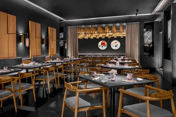 Innenansicht des Restaurants im Hilton Tulum Riviera Maya All-Inclusive Resort mit dunklen Wänden, Holztischen und Stühlen.