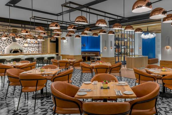 Innenansicht des Restaurants im Hilton Tulum Riviera Maya All-Inclusive Resort mit orangefarbenen Stühlen und Kupferlampen.