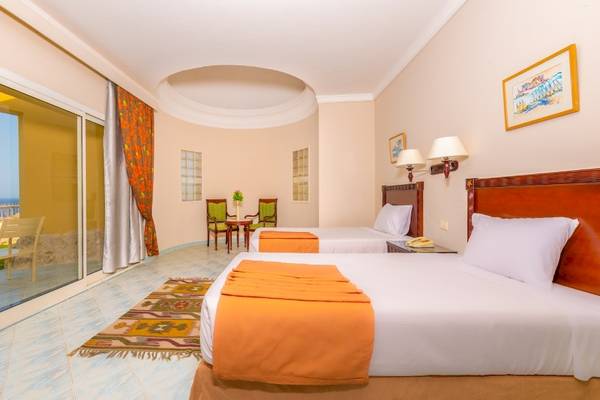 Zwei Betten in einem Zimmer des Siva Golden Bay Makadi Hotels mit einem Blick auf das Meer.