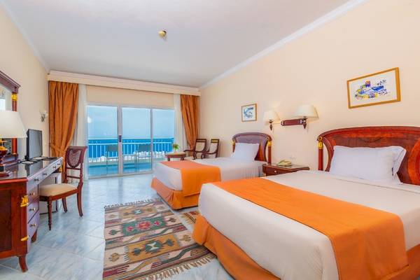 Hotelzimmer im Siva Golden Bay Makadi mit zwei Betten, Schreibtisch und Meerblick.