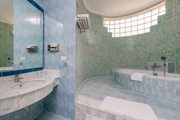 Badezimmer im Siva Golden Bay Makadi Hotel mit blauen Fliesen und Badewanne.