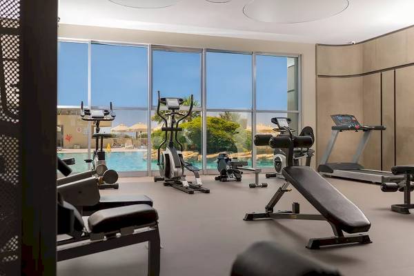 Fitnessraum im Melas Resort mit Blick auf den Pool und moderner Ausstattung.