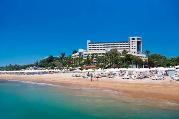 Strand des Melas Resorts mit vielen Liegestühlen und Sonnenschirmen.